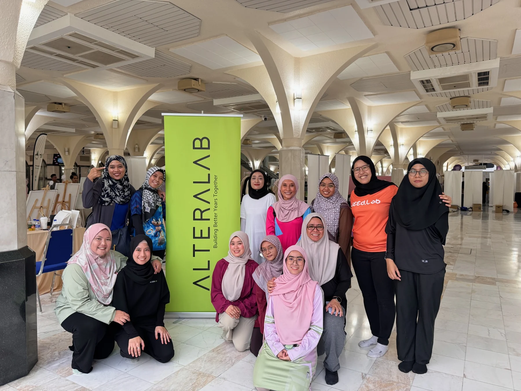 A group photograph beside the AlteraLab banner at WANITA ITU